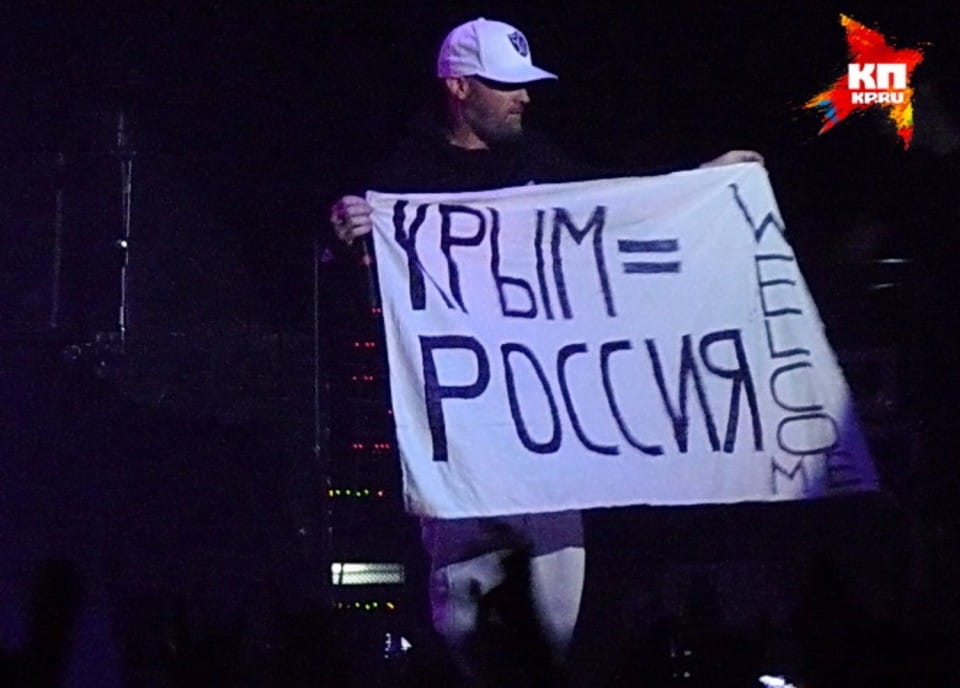 Fred Durst holding a flag that translates to "Crimea = Russia" with "Welcome" written down the left side.
